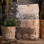Bag of premium cacti and succulent soil mix on a wooden surface with plants in the background